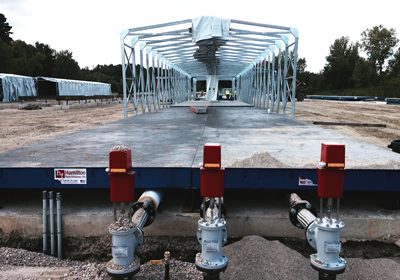 CAPTION: Preliminary New NY Bridge contract work has seen Unistress crews run steam lines with actuator valves and power to deck panel casting beds, secure collapsible tent enclosures, and test specimens.